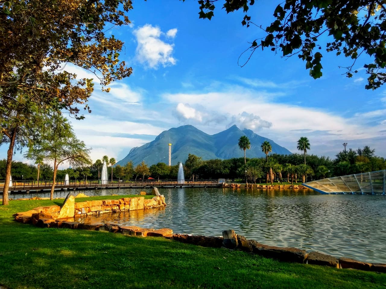 Parque con un lago y vistas de montañas, reflejando la presencia de MMTubería en infraestructuras de gran alcance que combinan naturaleza y urbanización en México.