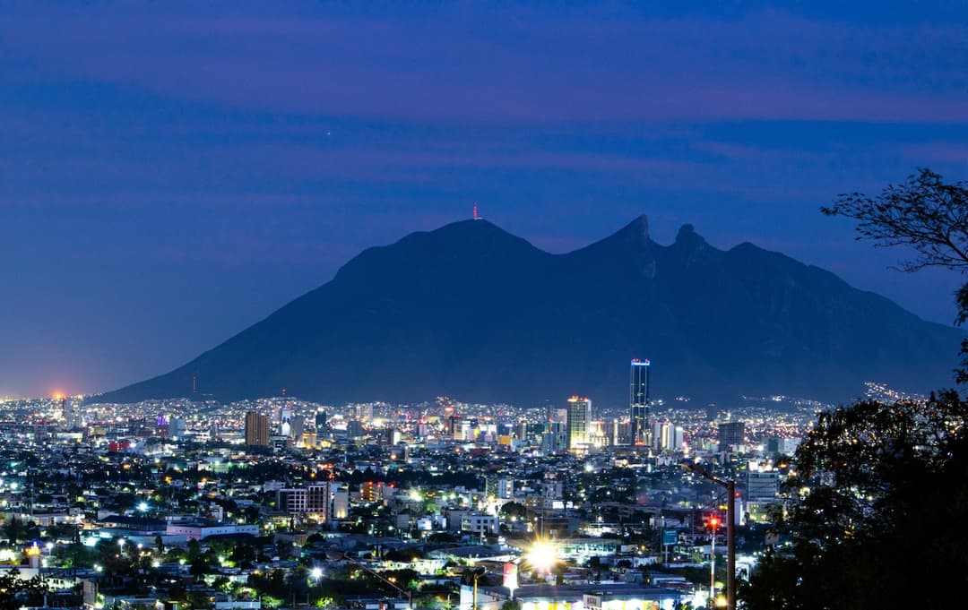 Vista nocturna de la ciudad con la icónica montaña en el fondo, simbolizando la presencia de MMTubería en todo el país, brindando soluciones de alta calidad en tuberías de acero a nivel nacional.