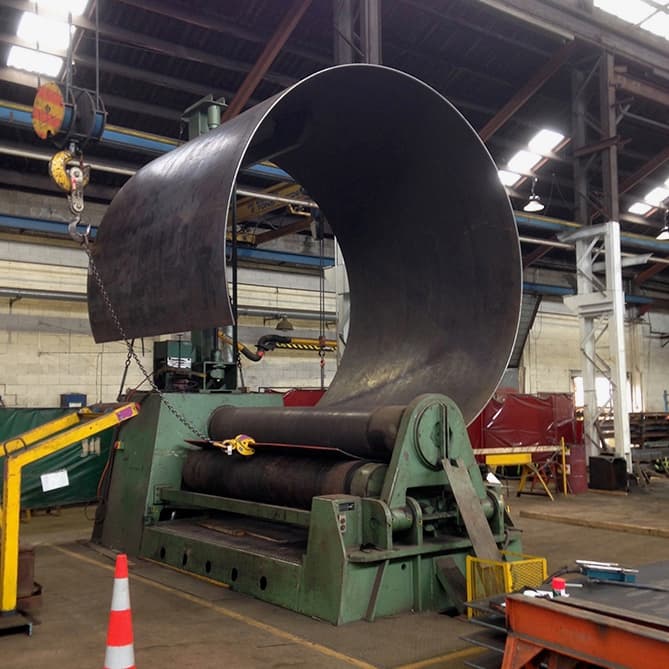 Proceso de curvado de lámina de acero para formar tubería, subrayando la precisión y tecnología avanzada utilizada por MMTubería en la producción de su tubería.