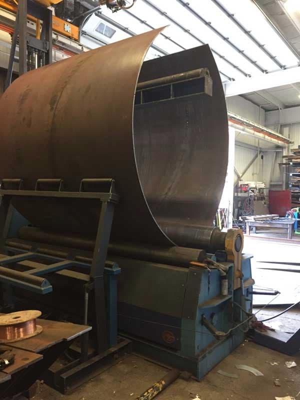 Lámina de acero en proceso de formación, destacando la precisión de MMTubería en la fabricación de tubería de alta calidad.