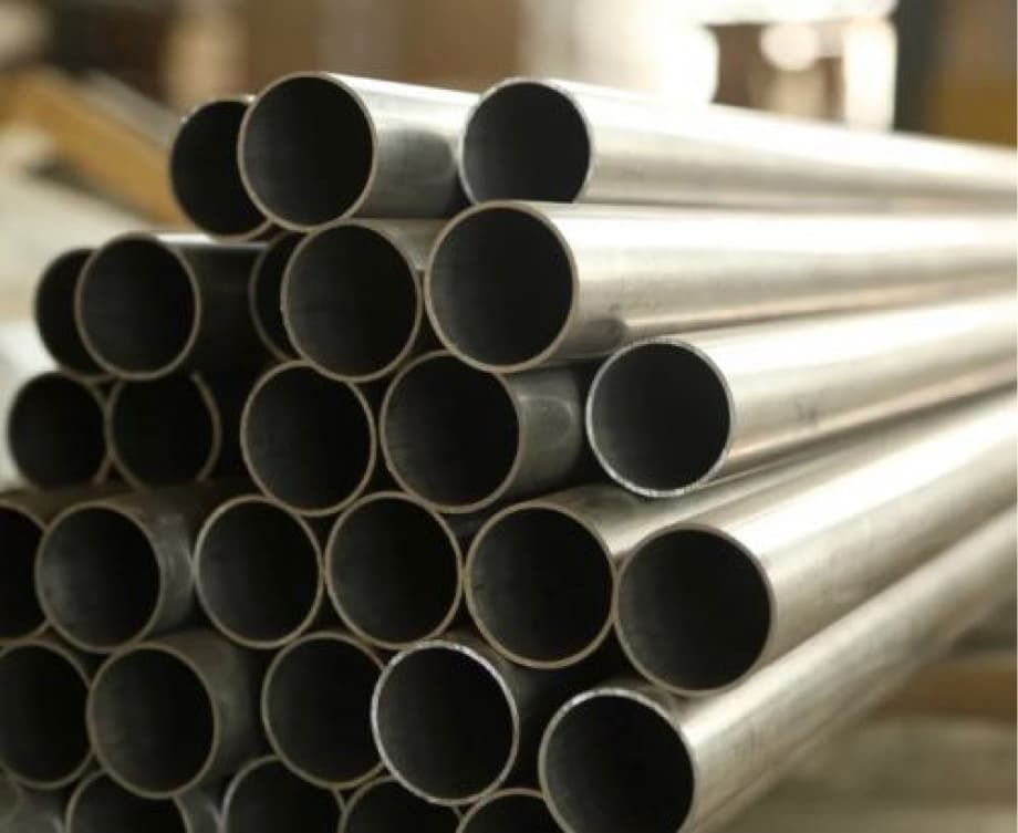 Tubos de acero apilados en un almacén, enfocando en la textura y calidad del material utilizado en sectores industriales y de construcción.