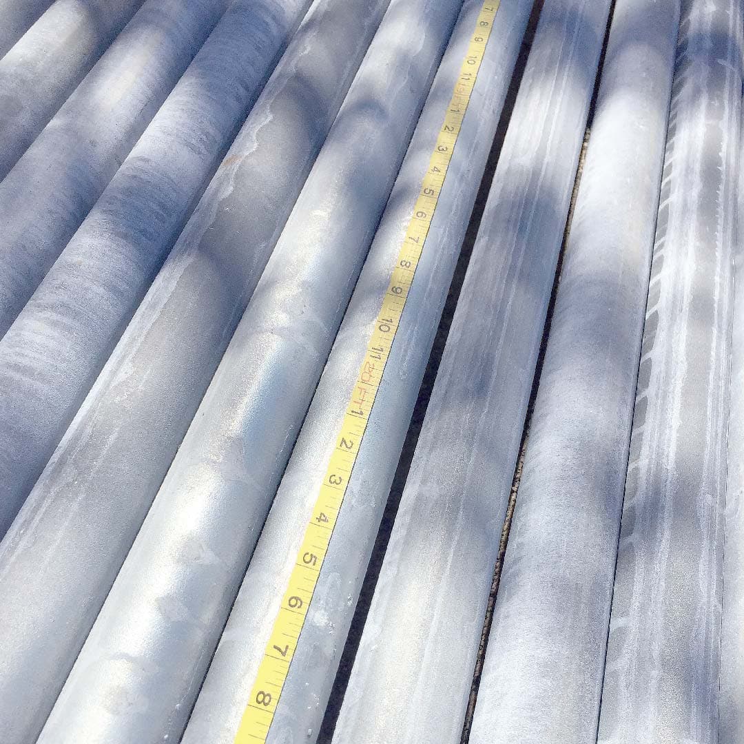 Pilas de tubos de acero en un depósito, ilustrando la capacidad de almacenamiento y disponibilidad de productos de alta calidad para proyectos de construcción y manufactura.