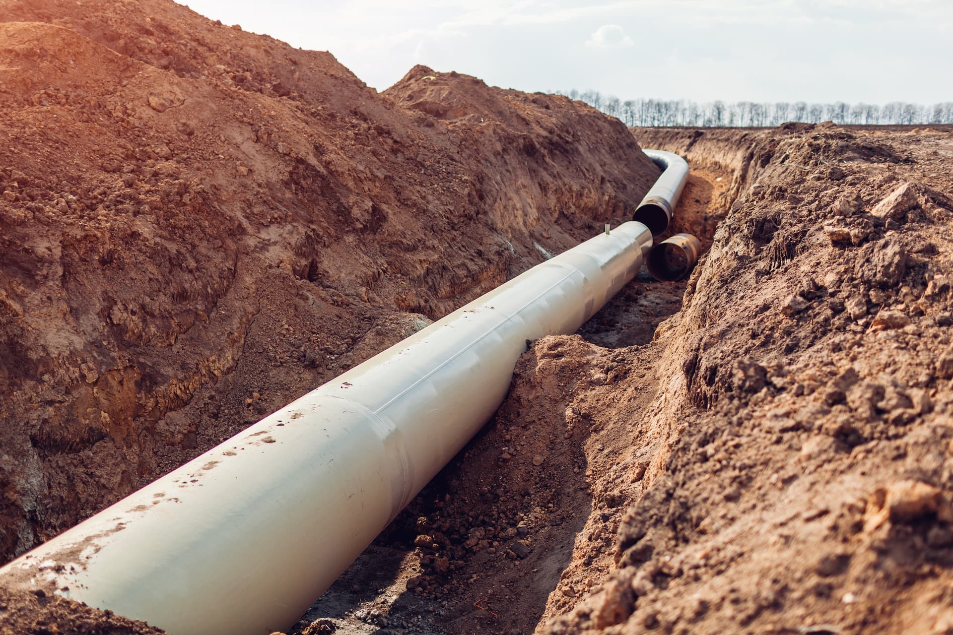 Tubería de gran diámetro siendo instalada en una zanja excavada, ilustrando el proceso de instalación en un proyecto de infraestructura, subrayando la durabilidad y la funcionalidad en entornos exigentes.