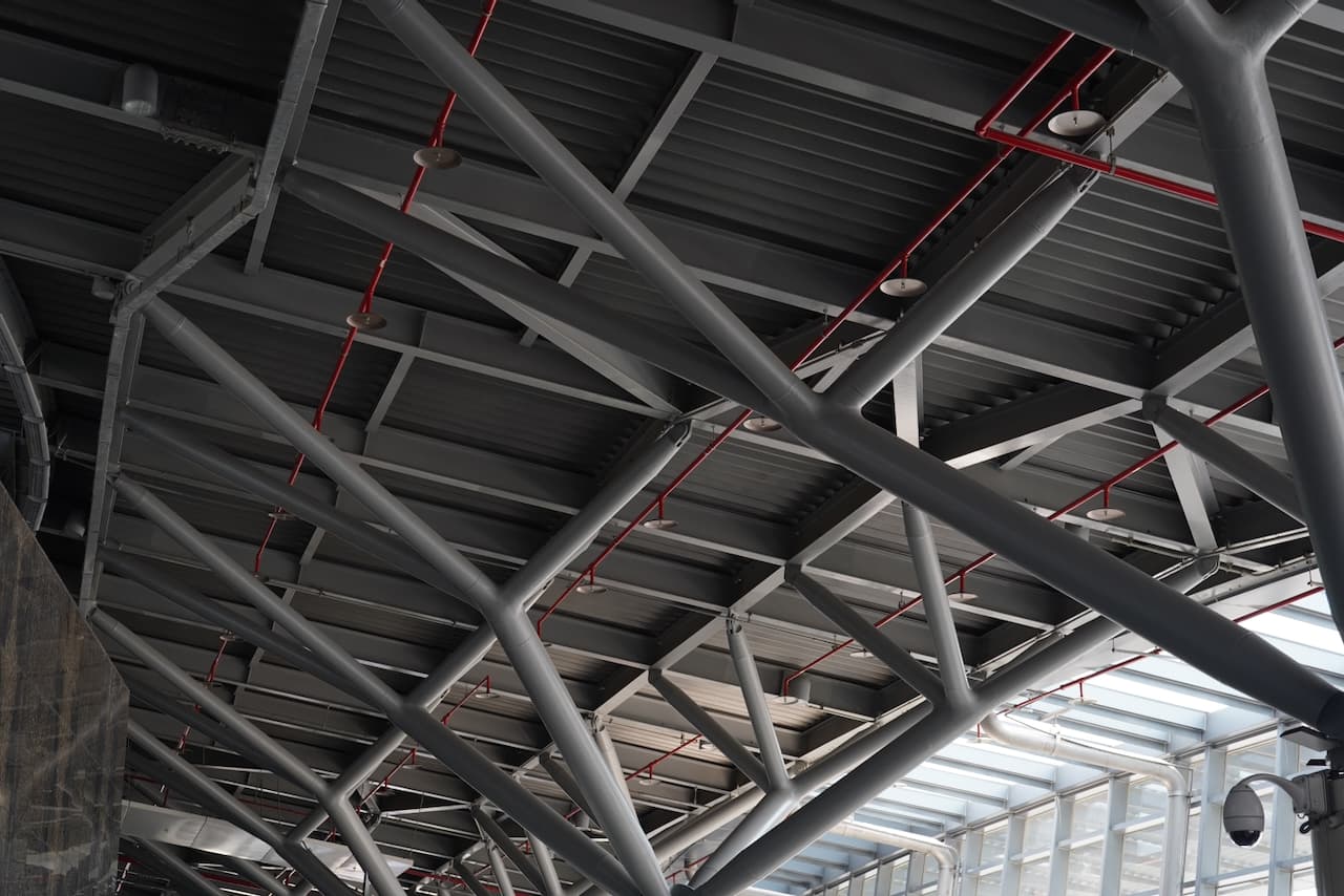 Detalle de la estructura metálica de un techo industrial con tuberías visibles.