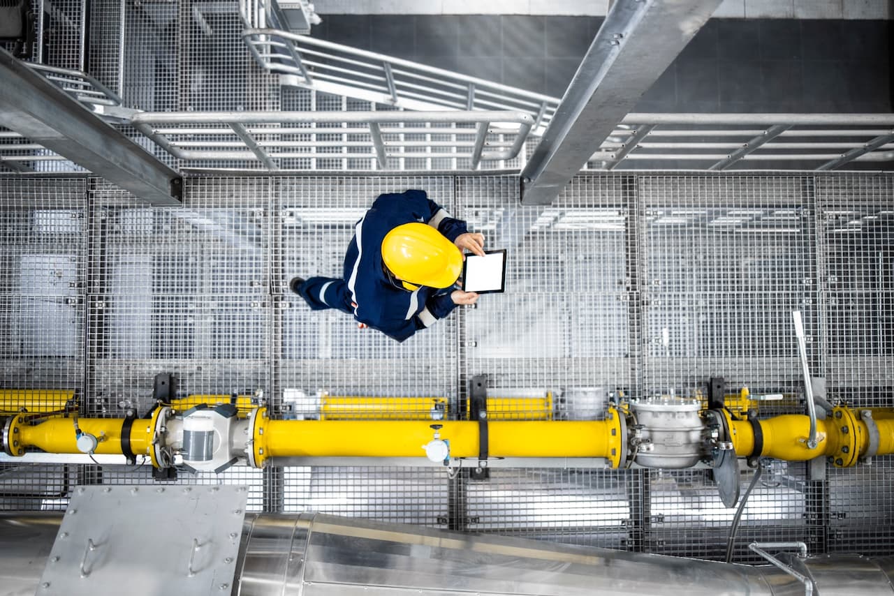 Técnico industrial inspeccionando una instalación de tuberías desde una vista superior, destacando control de calidad