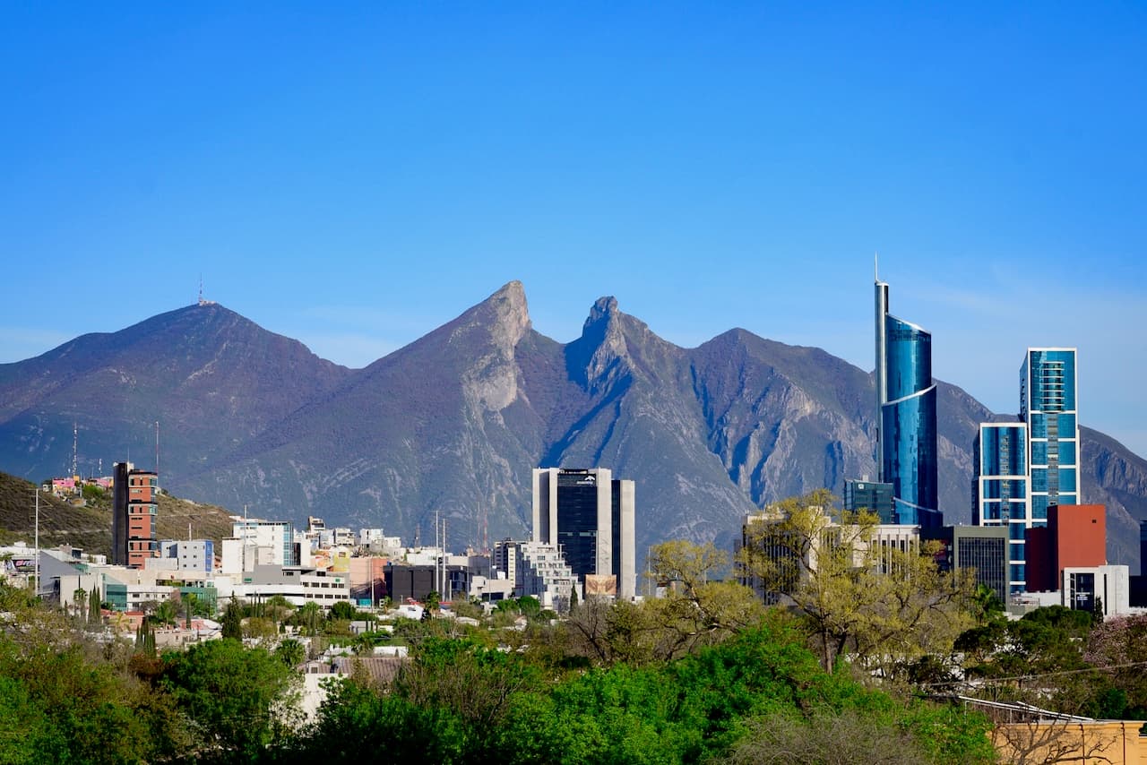 Paisaje urbano diurno con grandes montañas al fondo, destacando la robustez y durabilidad de las infraestructuras construidas con tuberías de acero de MMTubería.