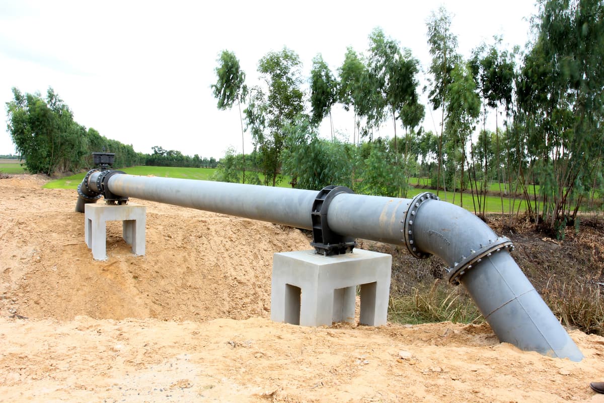 Gran tubería de acero instalada sobre bases de concreto en un entorno rural, destacando la durabilidad y funcionalidad de las tuberías de MMTubería en proyectos de gran escala.