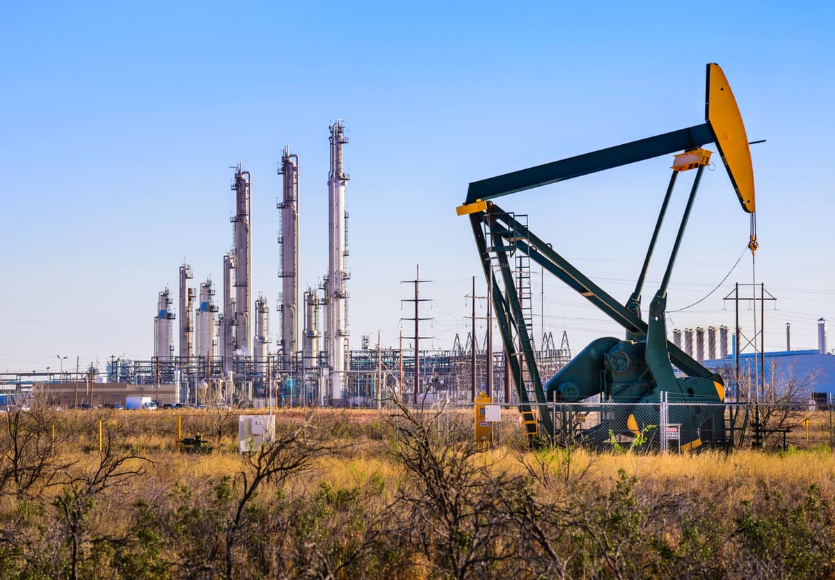 Vista de una bomba de petróleo con una planta industrial en el fondo, demostrando la robustez y uso industrial de las tuberías de acero de MMTubería.