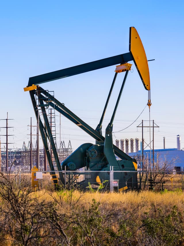 Maquinaria de extracción de petróleo en funcionamiento, con estructuras de tuberías de acero al fondo, evidenciando la aplicación de los productos de MMTubería en la industria energética.