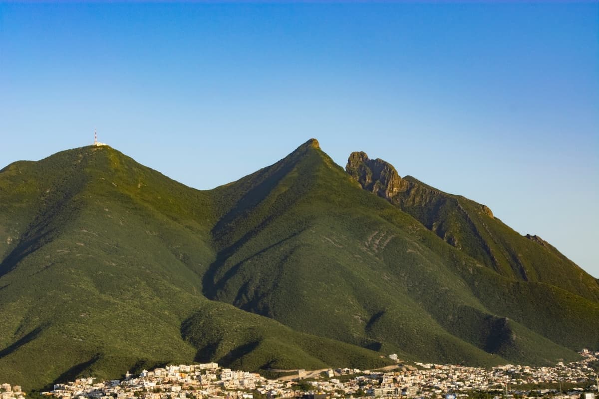 Paisaje de montañas verdes sobre un pueblo pequeño, ilustrando la belleza natural y el contexto geográfico donde se pueden aplicar proyectos de construcción utilizando estas tuberías.