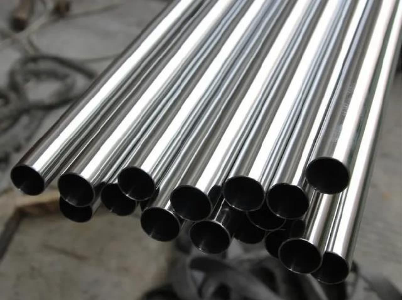 Pila de tuberías de acero almacenadas verticalmente, mostrando la uniformidad y el brillo del acero inoxidable listo para su distribución.