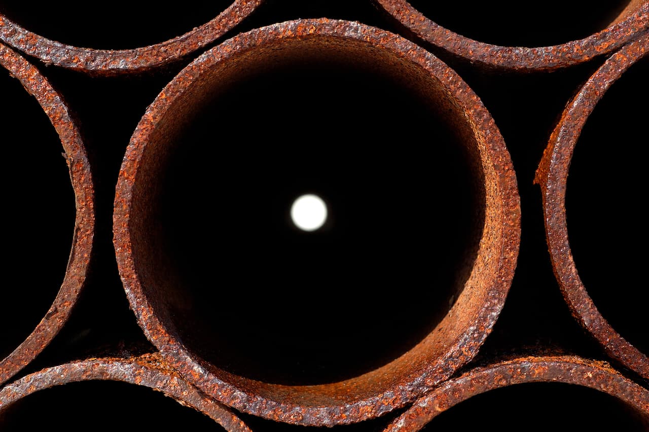 Tubos de acero alineados en un almacén, reflejando el riguroso proceso de fabricación y control de calidad de MMTubería para garantizar productos de alta durabilidad.