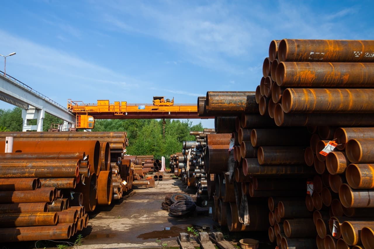 Barrera artística de barras metálicas y un segmento pintado de rojo en un parque, mostrando cómo los productos de MMTubería se integran en soluciones urbanas creativas y funcionales.