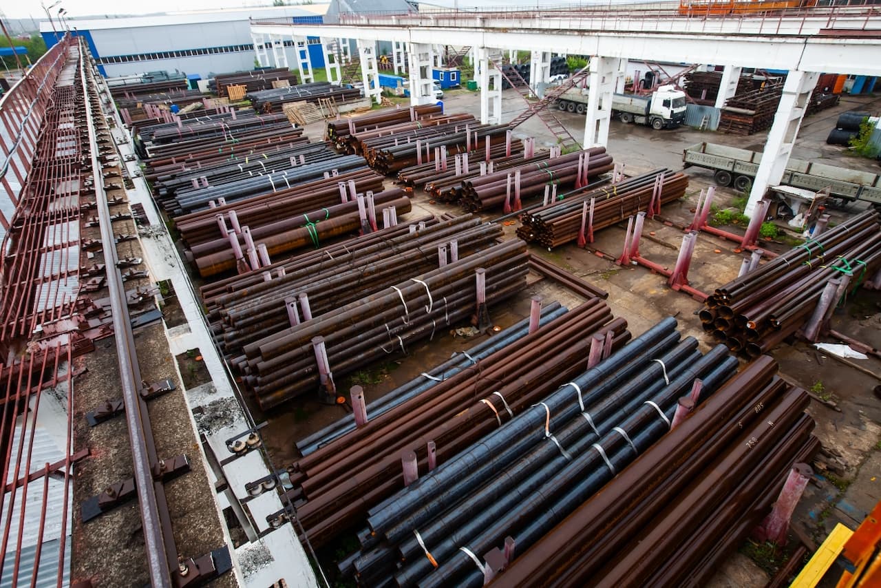 Amplia vista de tubos de acero apilados en un patio industrial, resaltando la amplia gama de productos de MMTubería y su preparación para cumplir con las demandas del mercado nacional.
