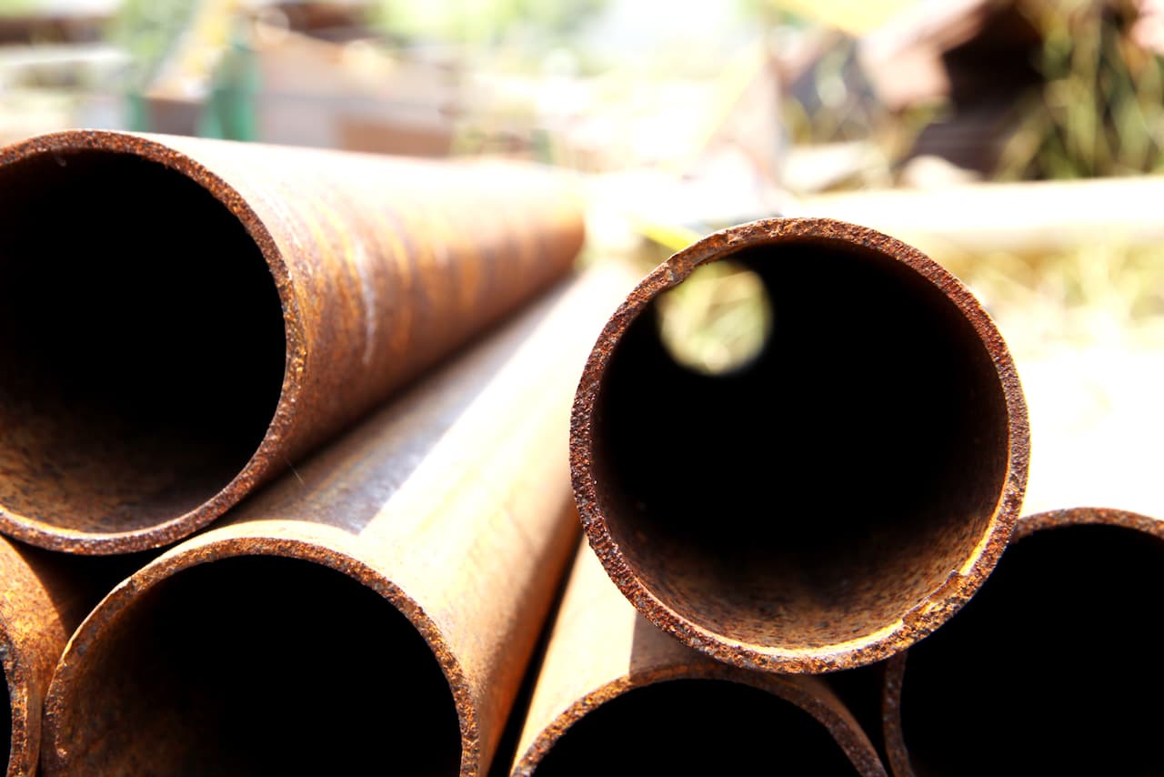 Columnas metálicas cilíndricas en una acera como parte de la infraestructura urbana, mostrando la versatilidad y la aplicación práctica de los productos de MMTubería en entornos urbanos.