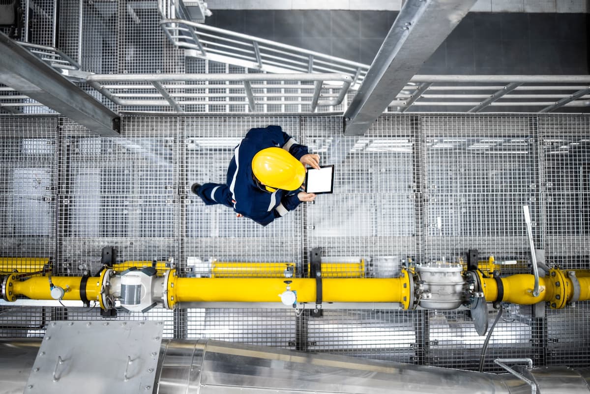 Operario industrial inspeccionando una tubería en una plataforma, destacando el compromiso de MMTubería con la calidad y seguridad en la instalación de sus productos a nivel nacional.