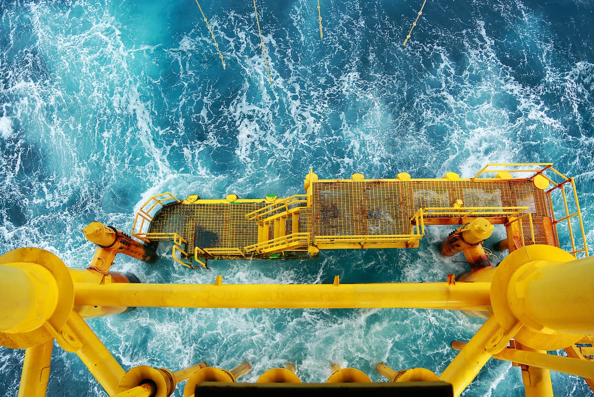 Vista aérea de una plataforma marina industrial con estructura amarilla, subrayando la durabilidad de los productos de MMTubería en ambientes marítimos y su proceso de fabricación especializado.